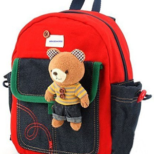 A toddler wearing a red safety walking leash and holding a red teddy bear while strolling down a sidewalk with her mom.